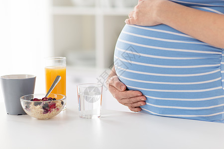 厨房孕妇孕妇抚摸她的孕肚在厨房健康早餐背景
