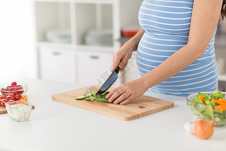 怀孕,烹饪食物健康饮食密切孕妇制作蔬菜沙拉切黄瓜的菜刀家里厨房的砧板上孕妇家煮蔬菜沙拉图片