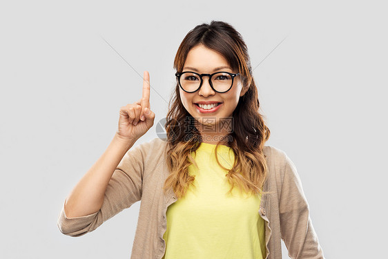 人,教育学校的快乐的亚洲妇女戴着眼镜学生灰色背景上指指点点戴眼镜的亚洲女人竖手指的学生图片