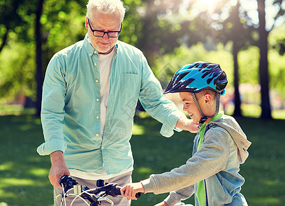 家庭,世代,安全人的快乐的祖父教男孩自行车自行车头盔夏季公园祖父男孩夏季公园骑自行车图片