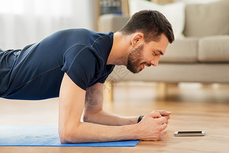 健身健康的生活方式男人看智能手机平板支撑图片