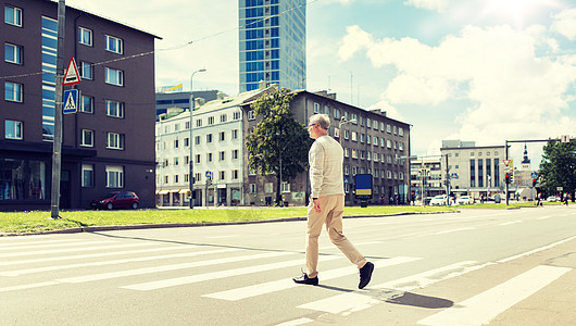 老人沿着城市人行横道行走图片