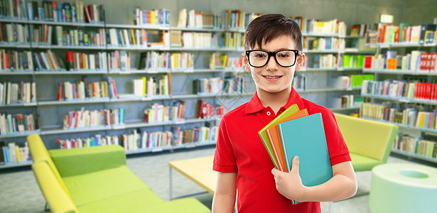 学校,教育人的微笑的小学生男孩穿着红色马球T恤,戴着眼镜,书图书馆背景的阅览室里图书馆戴眼镜带书的小学生图片
