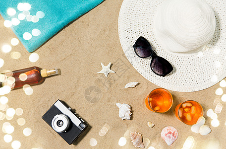 假期,旅行夏季两杯开胃酒鸡尾酒与冰,太阳帽与太阳镜,老式胶卷相机与防晒霜油贝壳海滩沙滩海滩沙滩上的饮料帽子照图片