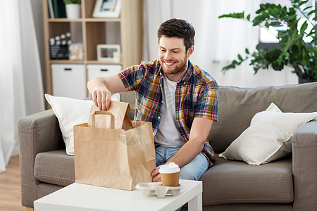 消费,饮食人们的微笑的男人家里打开外卖食品微笑的男人家里打开外卖食品图片