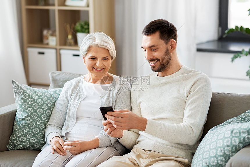 家庭,代人的快乐微笑的高级母亲成儿子与智能手机网络家里迈的母亲成的儿子家里智能手机图片