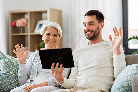 家庭世代人的快乐微笑的高级母亲成儿子家里的平板电脑上进行视频聊天迈的母亲成的儿子家用平板电脑图片