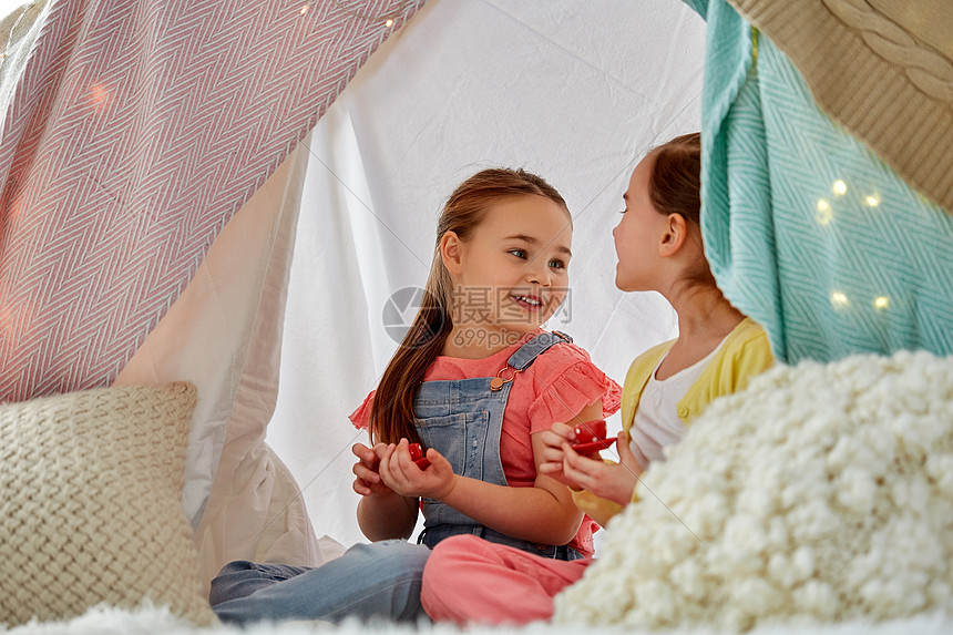 童潮湿的快乐的小女孩玩茶玩具陶器孩子们的帐篷家里小女孩家孩子们的帐篷里玩茶话会图片