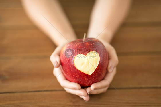食物,情人节健康密切的手,着成熟的红色苹果,雕刻的心形木制桌子上用雕刻的心紧握着苹果的手图片