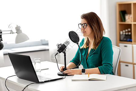 技术,大众媒体人们的戴着麦克风笔记本电脑的眼镜的女人录音室交谈录制播客演播室里麦克风录音播客的女人图片