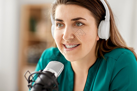 女DJ技术,大众媒体人的密切妇女与麦克风耳机交谈录音播客演播室演播室里麦克风录音播客的女人背景