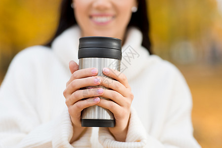 季节,热饮人们的接近快乐的轻女人喝咖啡热杯倒翁秋天公园快乐的轻女人秋天的公园喝咖啡图片