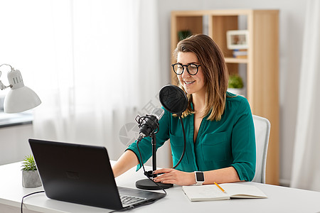 女DJ技术,大众媒体人们的戴着麦克风笔记本电脑的眼镜的女人录音室交谈录制播客演播室里麦克风录音播客的女人背景