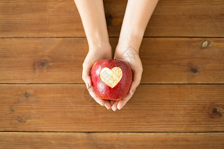 食物,情人节健康密切的手,着成熟的红色苹果,雕刻的心形木制桌子上用雕刻的心紧握着苹果的手图片