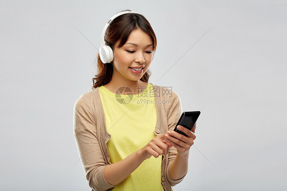 人,技术音频设备的快乐的亚洲轻妇女耳机听音乐智能手机灰色背景戴耳机听音乐的亚洲女人图片