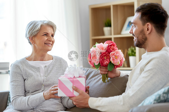 家庭母亲生日的微笑的成儿子家里给他的老母亲送礼物鲜花儿子给迈的母亲送礼物鲜花图片