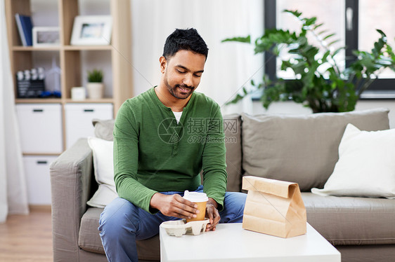 消费人们的微笑的印度男人带着外卖咖啡食物家印度男人带着外卖咖啡食物家图片