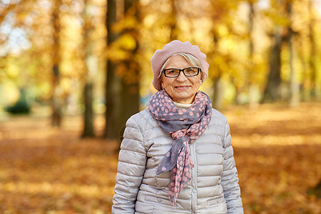 老退休季节秋季公园戴眼镜的快乐老妇女的肖像秋天公园快乐的高级女人的肖像图片