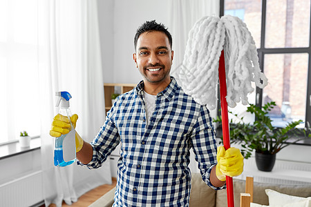 清洁,家务家务微笑的印度男子与拖把洗涤剂家里印度男人家里用拖把洗涤剂清洗背景图片