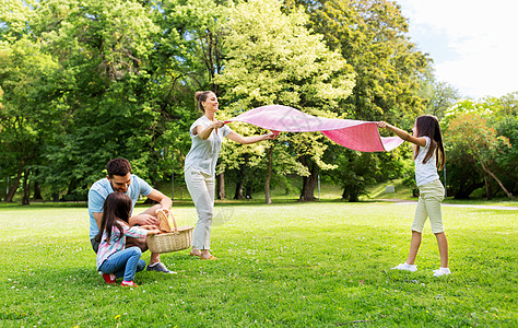家庭休闲人的快乐的母亲女儿夏季公园的草地上铺设野餐毯家人夏天的公园里铺设野餐毯图片