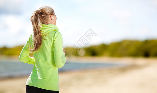 健身,运动健康的生活方式妇女与耳机运行听音乐夏季海滩背景耳机的女人公园跑图片