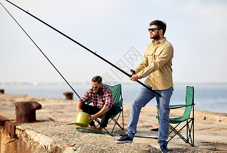 休闲人们的快乐的朋友与钓鱼竿码头海上码头上钓竿的快乐朋友图片