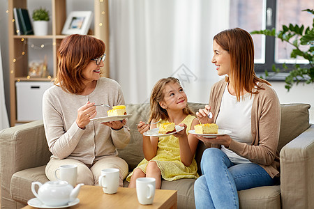 家庭世代食物微笑的母亲女儿祖母家里举行茶会吃蛋糕母亲女儿祖母吃蛋糕图片