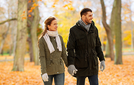 爱,关系人的微笑的夫妇牵着手,走过秋天的公园背景夫妇牵着手沿着秋天的公园散步图片