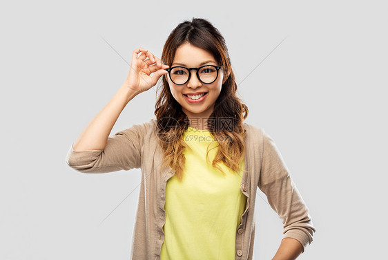 人,教育学校快乐的亚洲妇女戴眼镜学生灰色背景戴眼镜学生的快乐亚洲女人图片