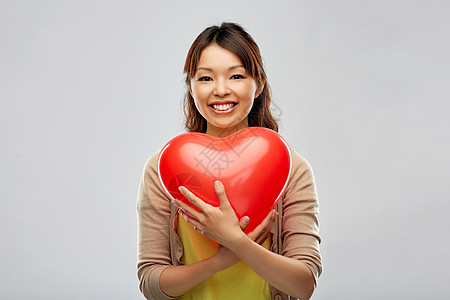 爱,情人节慈善快乐的亚洲轻妇女与红色心形气球灰色背景带红色心形气球的快乐亚洲女人图片