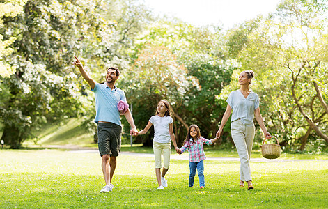 家庭休闲人的快乐的母亲带着野餐篮,父亲两个女儿夏季公园散步家人带着野餐篮夏天的公园散步背景图片