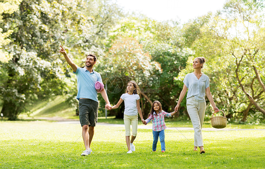 家庭休闲人的快乐的母亲带着野餐篮,父亲两个女儿夏季公园散步家人带着野餐篮夏天的公园散步图片