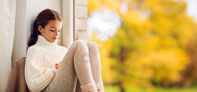 童,悲伤季节的悲伤的美丽女孩穿着毛衣坐家里的窗台上,秋天的背景下秋天,悲伤的女孩坐家里的窗台上图片