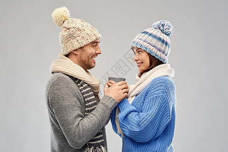 人们,诞节爱的幸福的浪漫夫妇戴着针帽围巾,着杯灰色背景穿着冬天衣服的幸福夫妇着杯图片