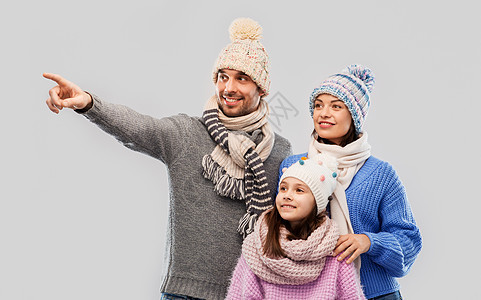 家庭,诞节冬天的衣服快乐的母亲,父亲小女儿穿着针帽子围巾灰色背景灰色背景下穿着冬天衣服的幸福家庭图片