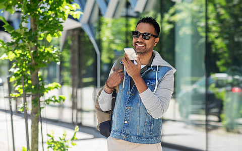 旅行,旅游生活方式的微笑的印度男子与背包用语音命令记录器智能手机城市街道男人城市的智能手机上重复语音信息图片