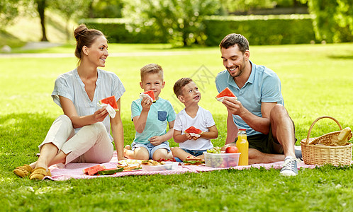 家庭休闲人的快乐的母亲,父亲两个小儿子夏天的公园野餐吃西瓜快乐的家庭夏天的公园野餐图片