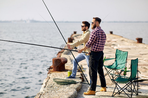 休闲人们的快乐的朋友与钓鱼竿码头海上码头上钓竿的快乐朋友图片