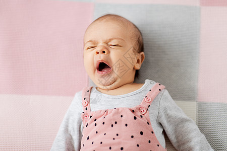 婴儿期人们的甜蜜的哈欠小女孩穿着粉红色的西装躺针毛毯上打哈欠的女婴穿着粉红色的西装躺毯子上背景图片