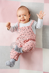 婴儿期人们的可爱的小女孩穿着粉红色的西装躺针毛毯上穿着粉红色西装的可爱女婴躺毯子上图片