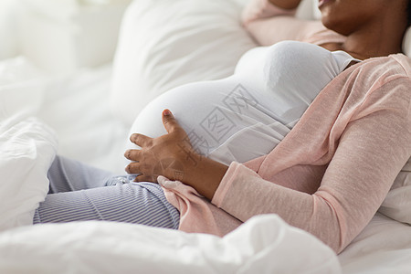 怀孕,人休息的快乐怀孕的非裔美国妇女躺床上的家庭卧室快乐的怀孕非洲妇女躺家里的床上图片