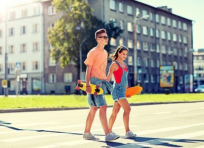 暑假,极限运动人们的快乐的青少夫妇与短现代巡洋舰滑板穿越城市人行横道轻夫妇城市街道上滑板图片