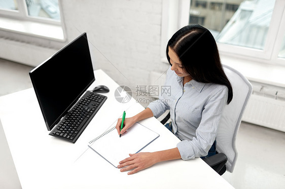 商业,教育人的微笑的女商人学生坐桌子上,办公室写笔记本上女商人办公室给笔记本写信图片