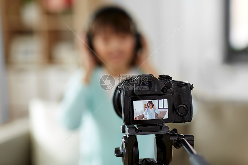 博客,视频博客人的相机记录视频博客微笑的亚洲女博主家里耳机评论带耳机的女博主制作视频博客图片