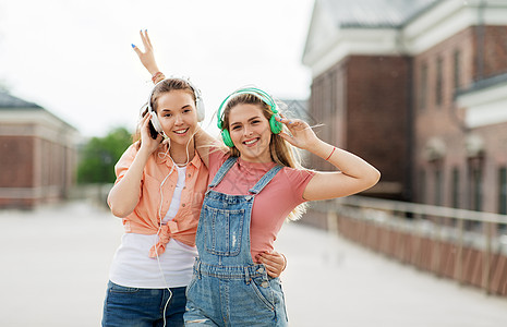 休闲,音乐友谊的快乐微笑的十几岁女孩最好的朋友戴着耳机拥抱城市街道夏天十几岁的女孩朋友城市耳机图片