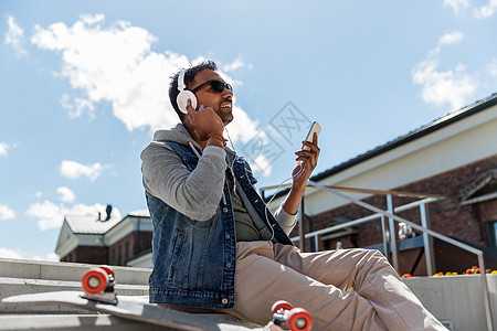 技术,休闲人的印度男子与智能手机,耳机长板听音乐屋顶屋顶上智能手机耳机的男人图片