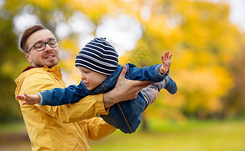 家庭,童父亲的快乐的父亲小儿子秋天的公园背景下玩户外玩父亲儿子秋天玩玩图片