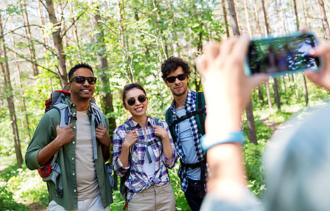 旅行,旅游徒步旅行群朋友与背包被智能手机拍摄森林带背包的朋友徒步旅行中被拍照图片