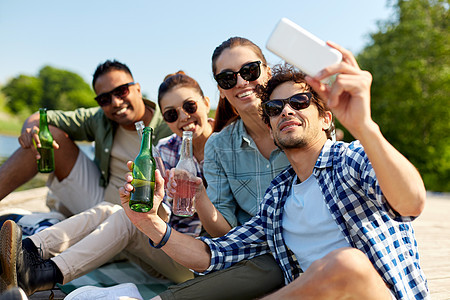 休闲,野餐技术朋友与饮料采取自拍智能手机湖墩夏季公园饮料的朋友用智能手机自拍图片