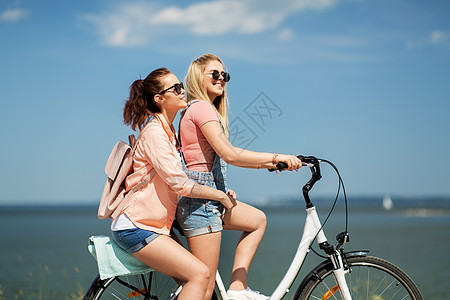 休闲友谊的快乐微笑的十几岁女孩朋友骑自行车海边夏天夏天十几岁的女孩朋友骑自行车图片